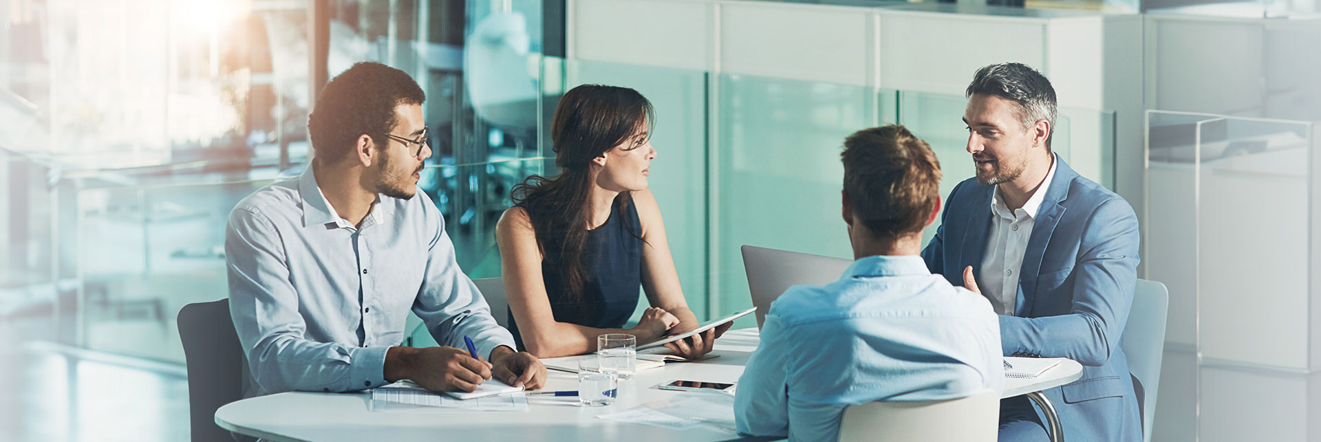 Réunion d'équipe sur une table blanche regroupant 4 collaborateurs